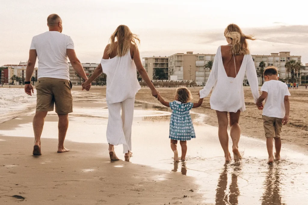 Familia paseando por la playa al atardecer
